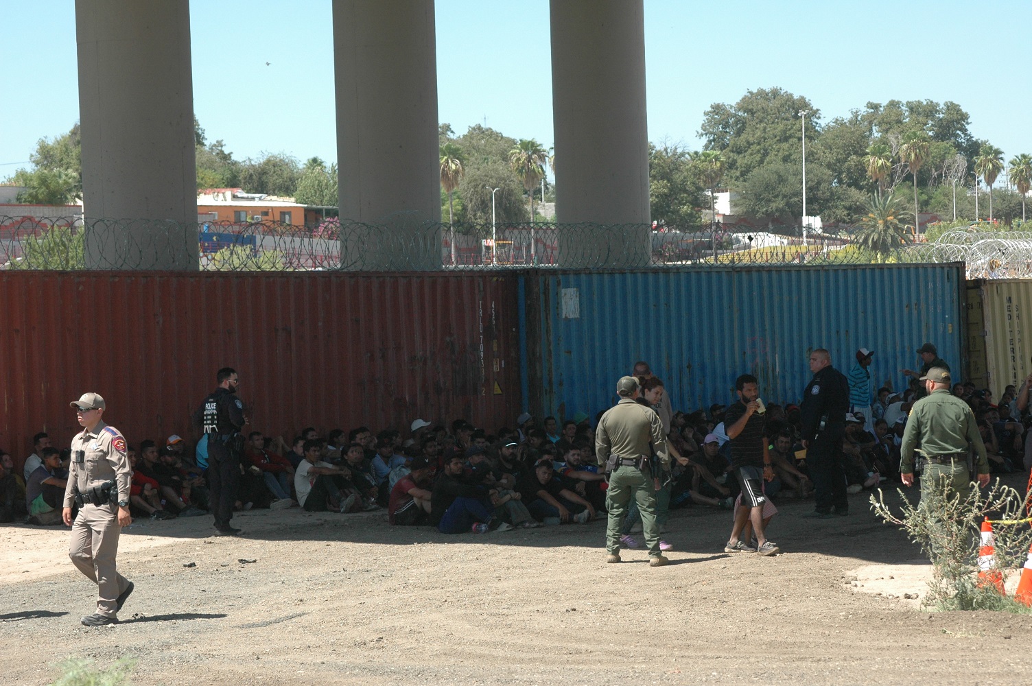 Migrants wait under one of the International Bridges